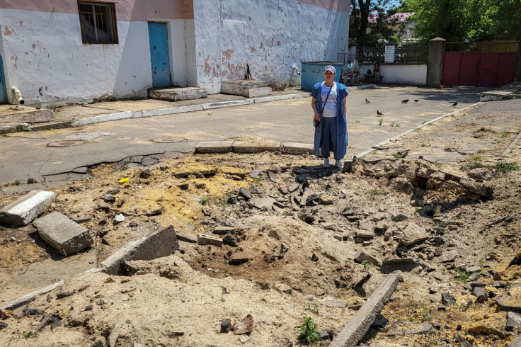 Deputy head of a Kherson's school stands next to the crater left by a shell hit near the school she used to work in Kherson