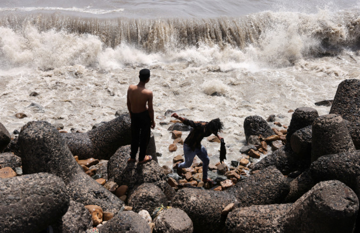 Boys watch waves hit the shore in Mumbai