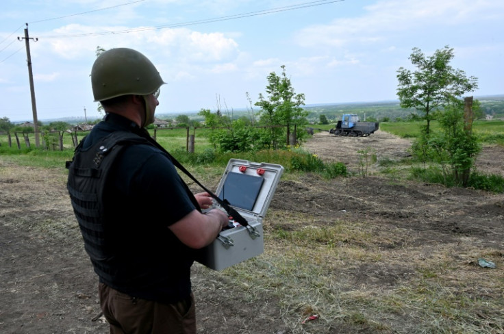 A Ukrainian deminer uses the remote system of a mine trawl to clear a field near Kharkiv