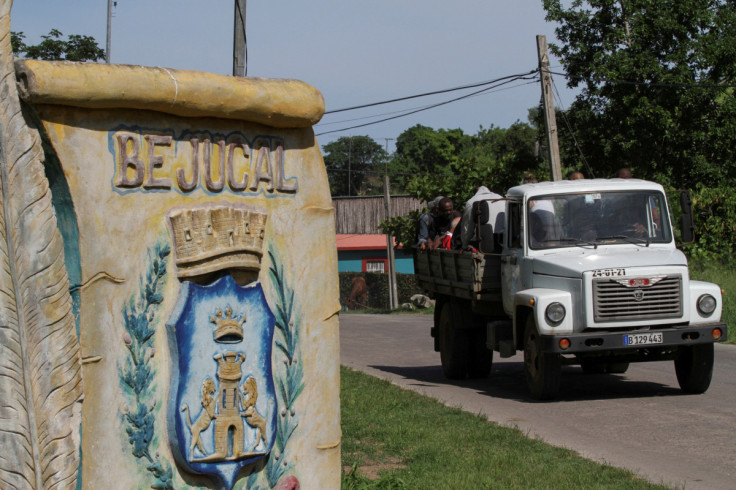 A truck passes by a sign at the entrance of Bejucal, Cuba