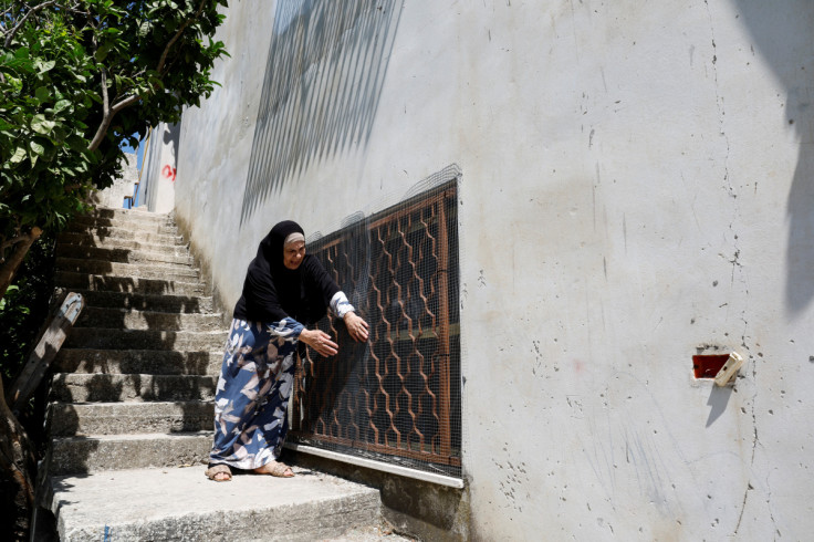A Palestinian woman straightens a mesh protecting a window of her home, following a spate of attacks by Israeli settlers in the Palestinian village of Burqa