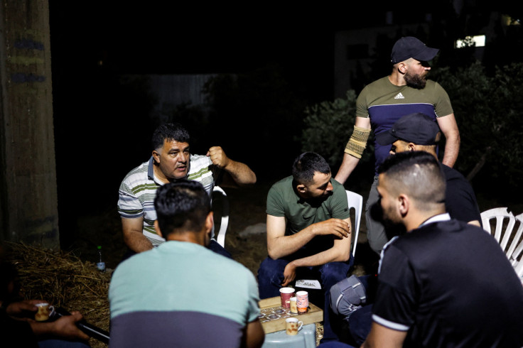 A group of Palestinian men chat during a nightwatch following a spate of attacks by Israeli settlers, in the Palestinian village of Burqa