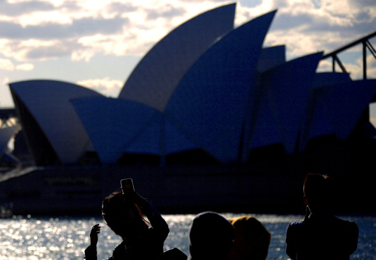 Chinese and Malaysian tourists take photographs of the Sydney Opera House from a viewing area located on Sydney Harbour, Australia