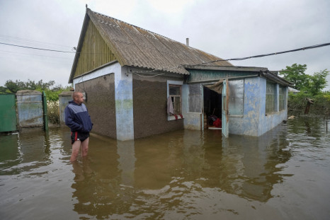 A local resident looks at his flooded building after the Nova Kakhovka dam breached in the flooded village of Afanasiivka