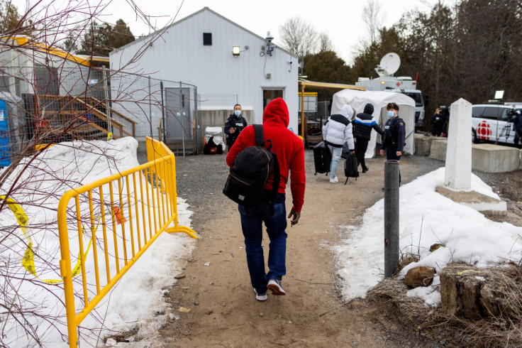 People wait for transport to cross into Canada at Roxham Road, in Plattsburgh