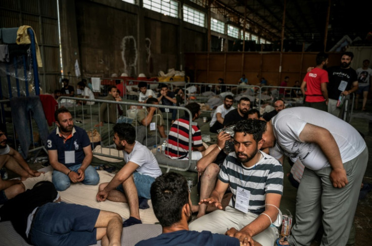Survivors of the shipwreck wait inside a warehouse at the port of Kalamata