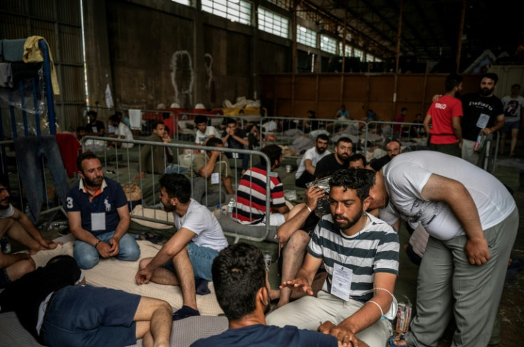 Survivors of the sinking sit inside a warehouse at the port of Kalamata in Greece