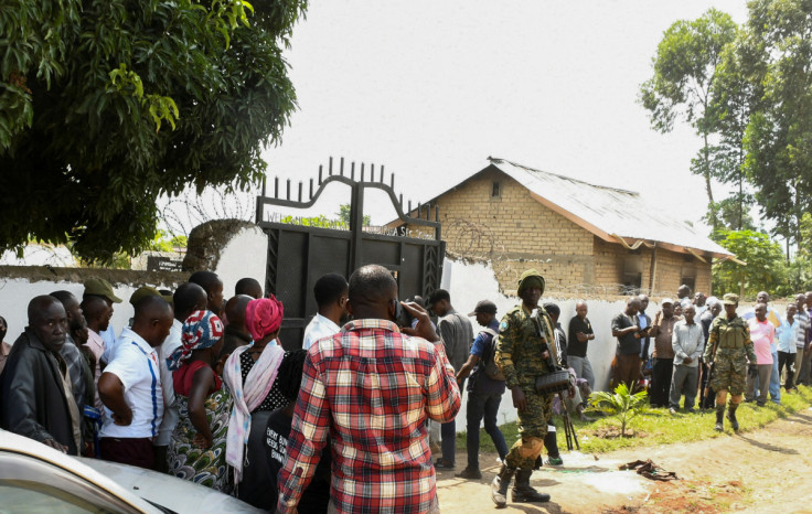 Ugandan security forces stand guard as locals gather at the cordoned scene outside the Mpondwe Lhubirira Secondary School