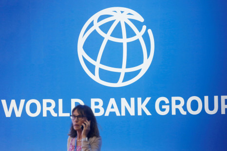 A participant stands near a logo of World Bank at the International Monetary Fund - World Bank Annual Meeting 2018 in Nusa Dua