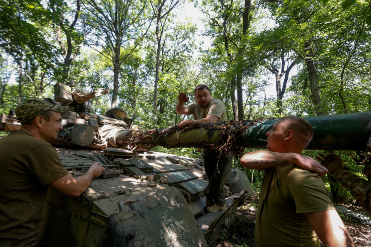 Ukrainian servicemen talk next to a T-80 main battle tank captured earlier from Russian troops, at a position near the front line town of Bakhmut