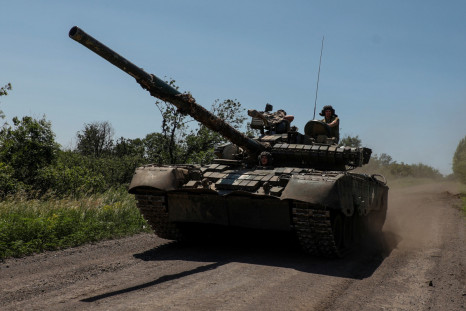 Ukrainian servicemen ride in a T-80 main battle tank captured earlier from Russian troops, along a road near the front line town of Bakhmut