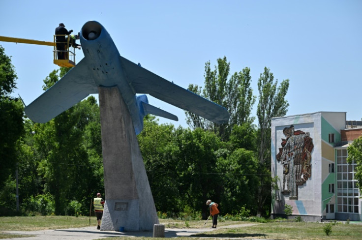 Municipal workers paint a fighter aircraft on a Soviet-era monument in Kramatorsk in east Ukraine