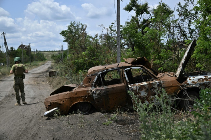 A Ukrainian serviceman walks past a destroyed car in the recaptured Donetsk village of Storozheve