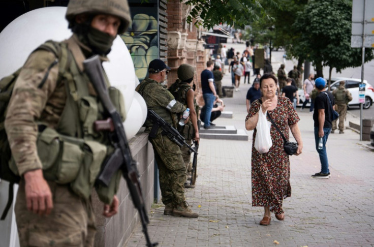 A resident walks by members of the Wagner mercenary group in the southern Russian region of Rostov-on-Don