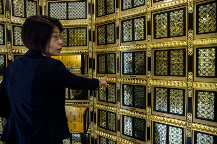 An employee at the Shan Sum columbarium points to the ornate niches that hold funeral urns