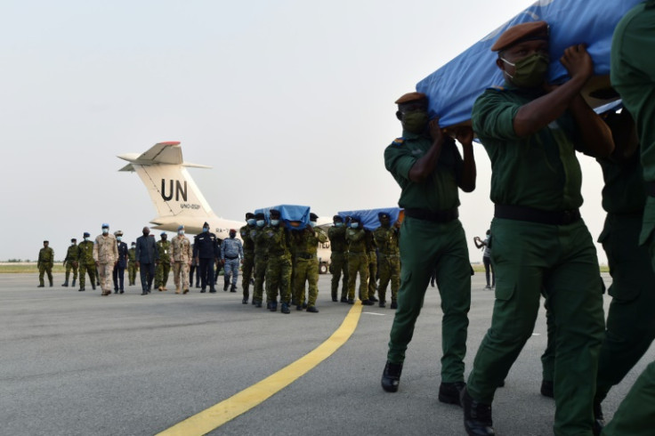 Ivorian soldiers carry coffins wrapped with United Nations flags out of a UN plane on February 22, 2021 at a military base in Abidjan, at the arrival of the bodies of four Ivorian peacekeepers killed in Mali