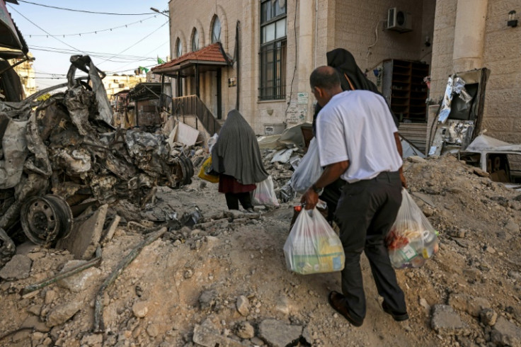 People carry bags of food and basic supplies handed out by a local organization