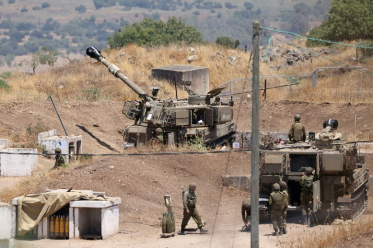 Israeli soldiers stand near army self-propelled artillery vehicles on the outskirts of Kiryat Shmona near Israel's border with Lebanon on July 6, 2023