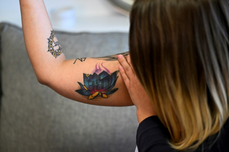Sex trafficking survivor Breanna Cole shows a tattoo of a colorful lotus flower that covers a former branding tattoo that read “381”