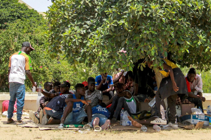 Sub-Saharan African migrants rest under the shade of a tree to avoid the heat during a protest against their dire conditions in Tunisia's coastal central city of Sfax