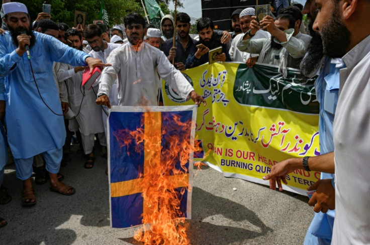 People burn a banner of Sweden's flag during a demonstration in Peshawar