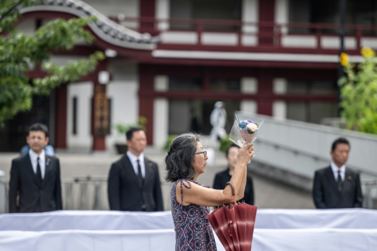 Visitors formed a long queue outside Tokyo's Zojoji Buddhist temple, offering flowers before framed pictures of a smiling Abe