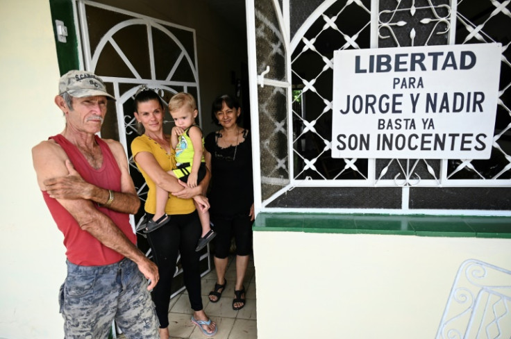 Marta Perdomo (R), mother of jailed brothers Nadir Martin and Jorge Martin, stands near a poster demanding freedom for her sons detained two years ago