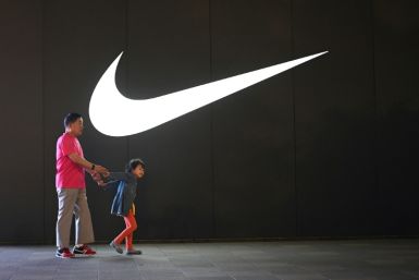 An elderly man and a child walk past a Nike logo in Wangfujing shopping district in Beijing in June 2021