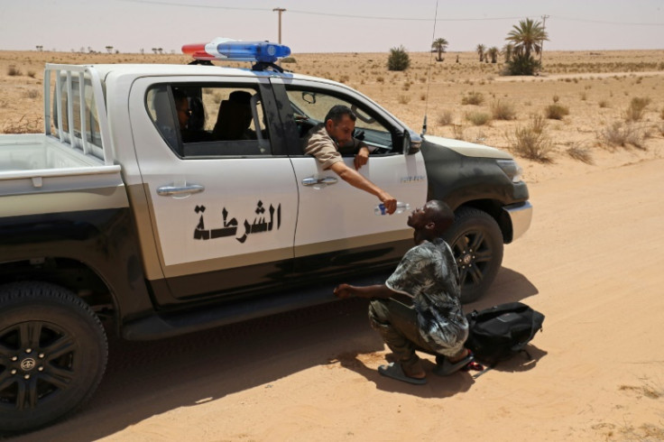 A Libyan border guard gives water to a migrant during a rescue operation in an uninhabited area near the town of Al-Assah on the border with Tunisia