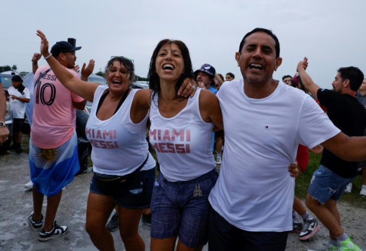 Fans dance under the rain outside DRV PNK Stadium in Fort Lauderdale, Florida, where Argentine star Lionel Messi was introduced by hs new club Inter Miami of Major League Soccer