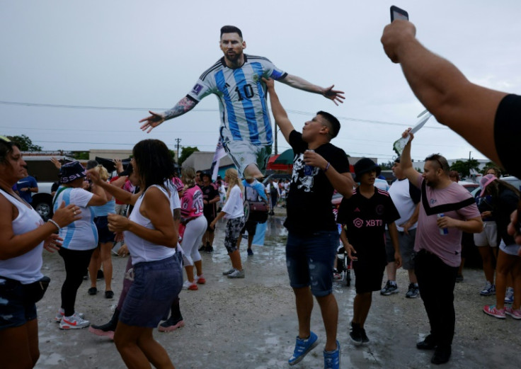 Fans carry a cardboard cutout of Lionel Messi outside DRV PNK Stadium before the star was presented to supporters following his move to Inter Miami of Major League Soccer