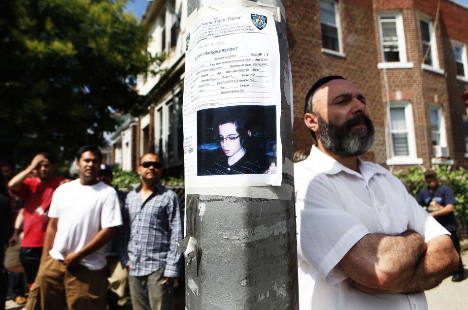 People stand near the home of the suspected killer of Kletzky in the Orthodox Jewish section of Borough Park in the Brooklyn borough of New York