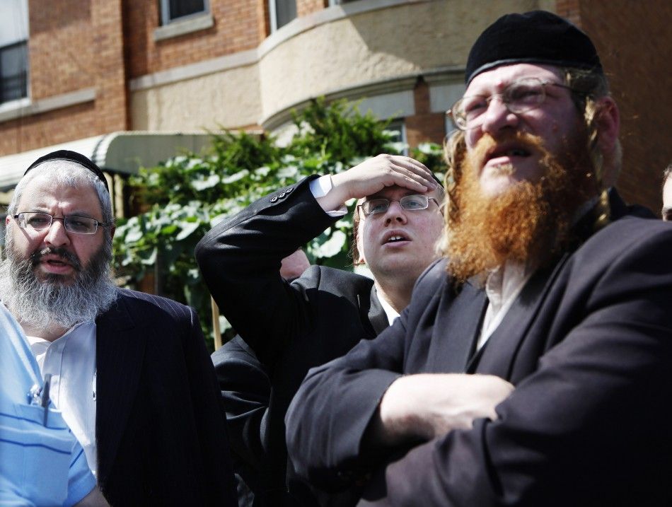 Men stand near the home of the suspected killer of Kletzky in the Orthodox Jewish section of Borough Park in the Brooklyn borough of New York