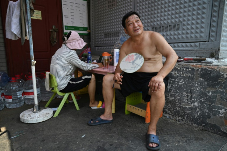 A man fans himself in an alley in Beijing as the Chinese capital bakes under a record-breaking run of high temperatures