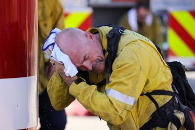 A San Bernardino County firefighter wipes his head as the Oak Fire burns near Fontana, California