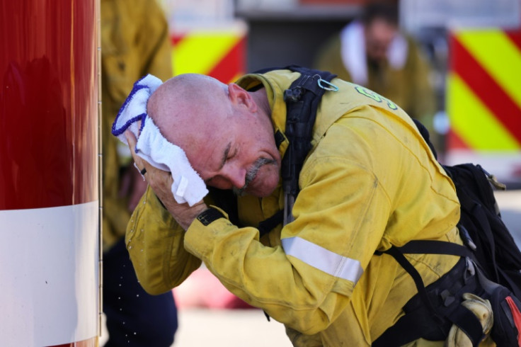 A San Bernardino County firefighter wipes his head as the Oak Fire burns near Fontana, California