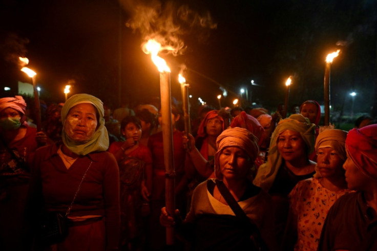 Women from the Meira Paibis group of the Meitei community in India's Manipur state gather in front of the partially burned house of a man accused of abusing two Kuki women after a video of the incident emerged