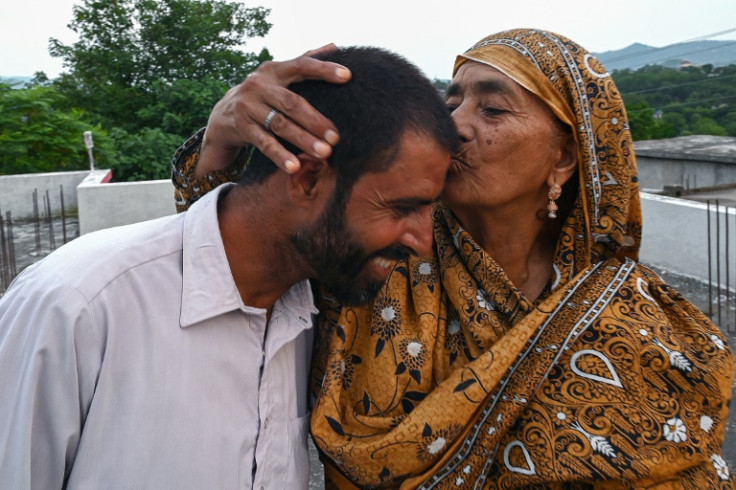 Muhammad Naeem Butt, who gave up on a perilous attempt to reach Europe, is kissed by his mother Razia Latif at their home in Pakistan