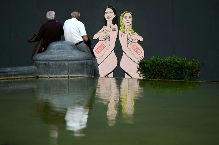 Passers-by look at a mural painting by Italian artist- activist aleXsandro Palombo, depicting Prime Minister Giorgia Meloni (R) and Democratic Party (PD) Secretary Elly Schlein (L) naked and pregnant as debate rages over surrogacy