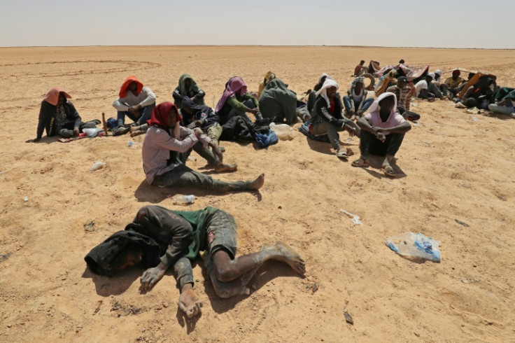 Migrants from sub-Saharan African countries who say they were abandoned in the desert by Tunisian authorities without water or shelter sit in an uninhabited area near Libya's border town of Al-Assah on July 16, 2023