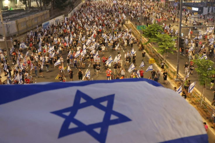 Protesters lift flags as they march against the Israeli government's judicial overhaul plan in Tel Aviv on July 29, 2023