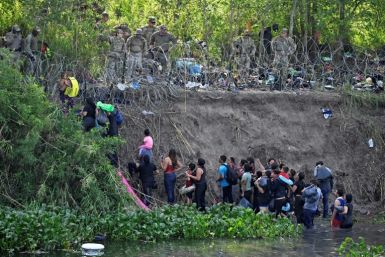 Migrants who crossed the Rio Bravo river (Rio Grande in the US) are stopped by members of the US National Guard reinforcing a barbed-wire fence along the US-Mexico border river in May 2023.