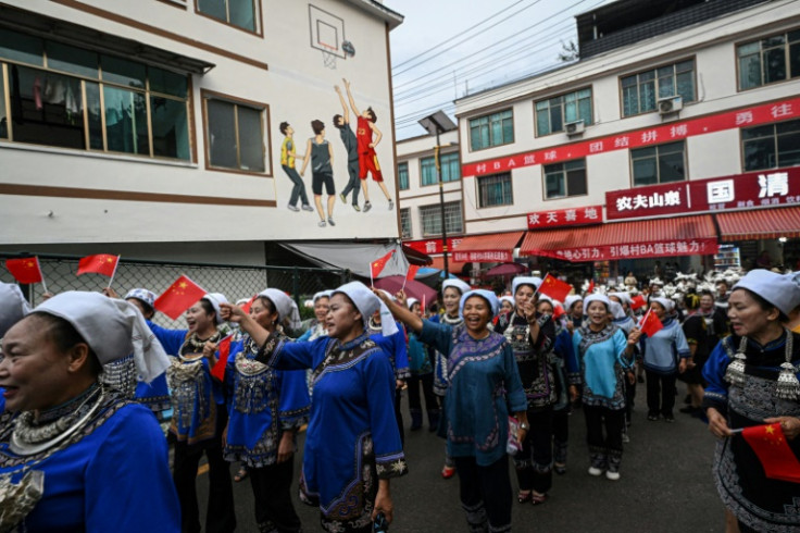 Performers clad in traditional Miao ethnic minority garb arrive outside the stadium