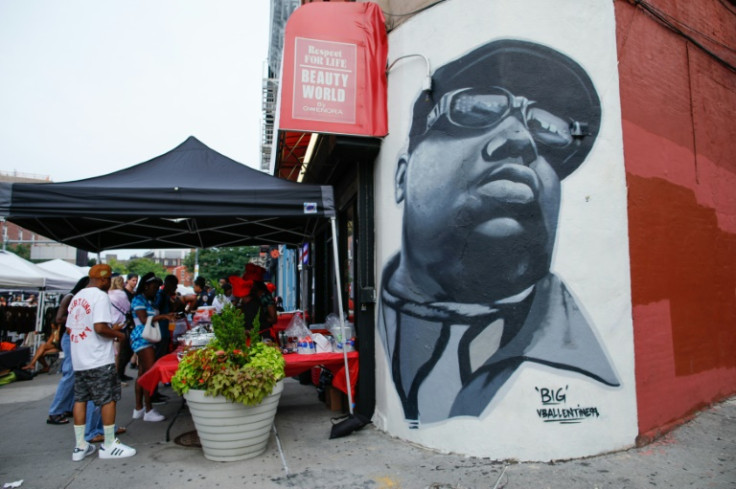 A mural of The Notorious B.I.G. by artist Vincent Ballentine is seen as people buy food during the 50 years of Hip-Hop celebration block party in Brooklyn, New York, on August 5, 2023
