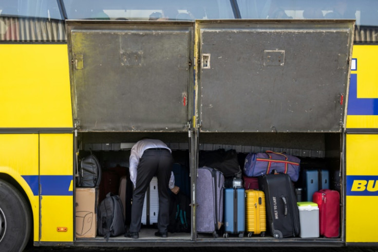 A bus driver stows luggage in a compartment before departing for Minsk