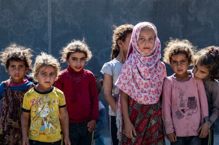 Girls stand next to a tent at the Al-Yunani makeshift camp in Syria's northern province of Raqa