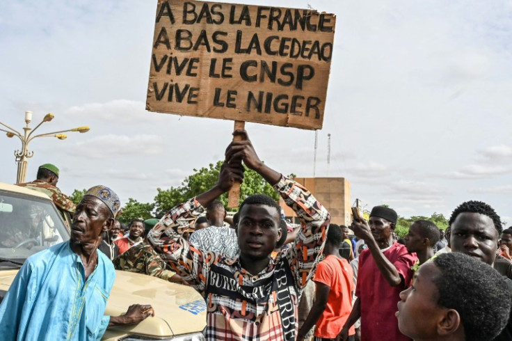 A supporter of Niger's ruling military, the CNSP, holds a placard with anti-French and anti-ECOWAS slogans at Sunday's rally
