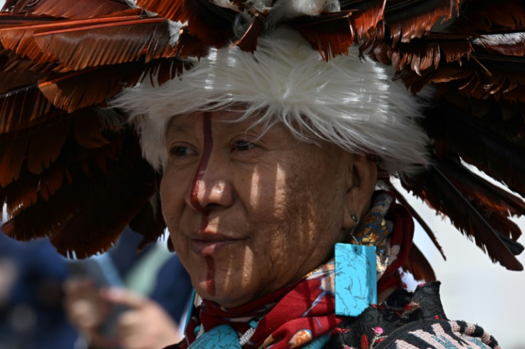 A person in Native American head dress looks on as President Joe Biden announces he is putting the brakes on uranium mining in now-protected Arizona lands around the Grand Canyon