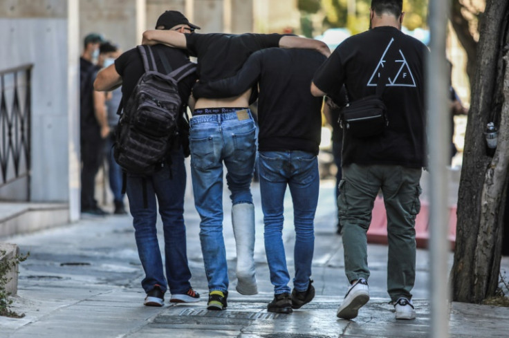 An injured fan is helped by fellow football fans after leaving Athens police headquarters