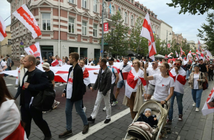 Belarusian people and their supporters, many with historical Belarusian flags, take part in a march in Vilnius in neighboring Lithuania three years after a disputed election and protests